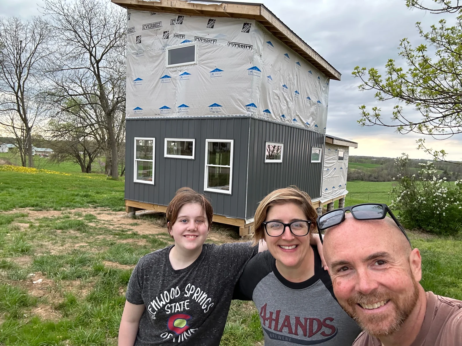 Oona, Calleen, and Brian in front of the house after siding had started.