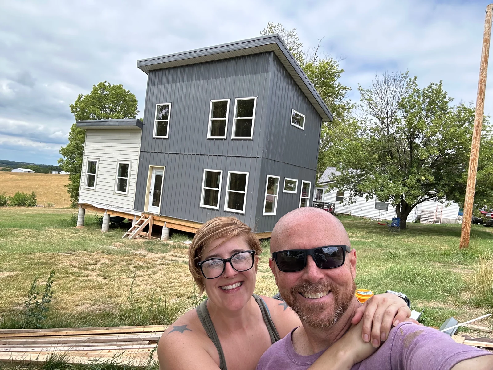Brian and Calleen in front of the house with gray fiber cement siding installed.