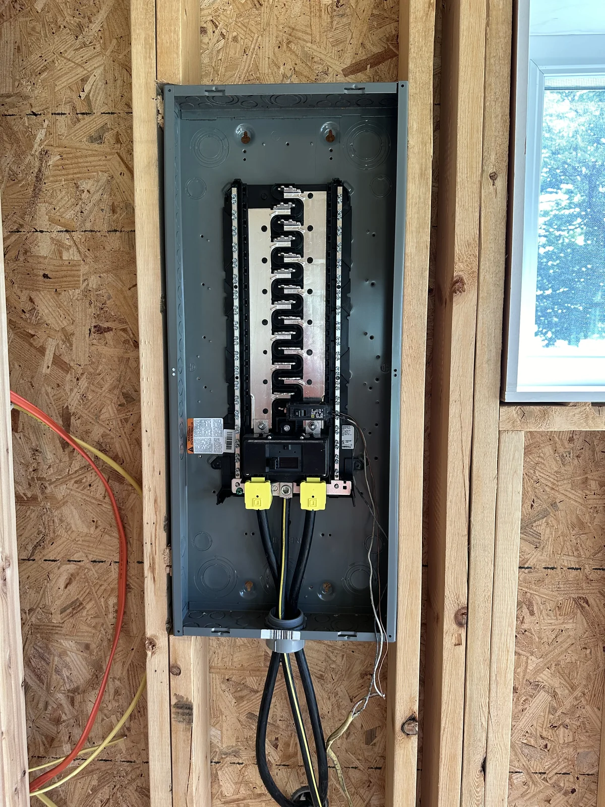 The installed electric panel inside the unfinished wall framing.